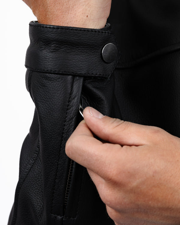 Close-up of a person adjusting a black leather cuff of leather motorbike jacket