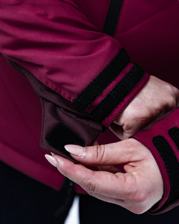 Close-up of a hand wearing a burgundy glove with black trim.