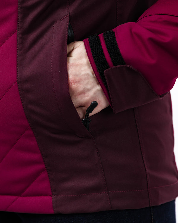 Close-up of a person wearing a maroon jacket with a white background