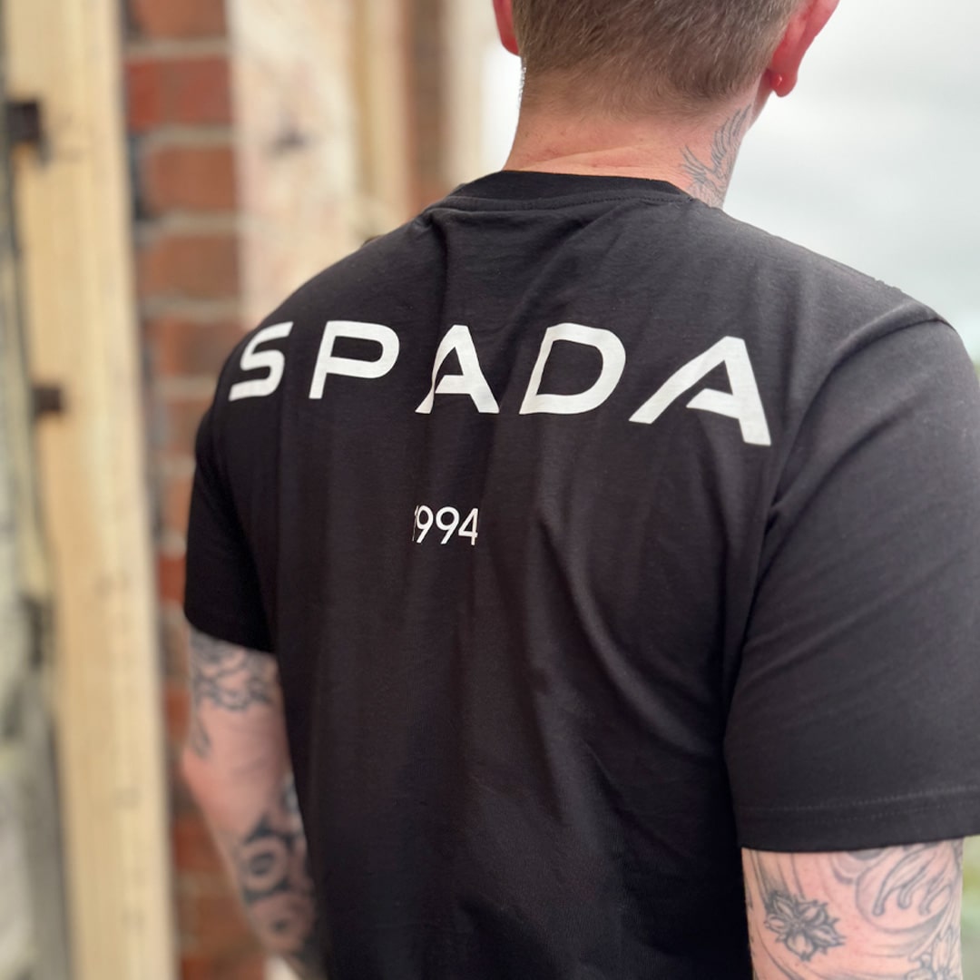 back of black t-shirt with large white spada logo across the back