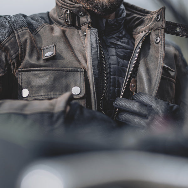 Biker zipping up Crossguard jacket over thermal layer, demonstrating layering compatibility for cold rides