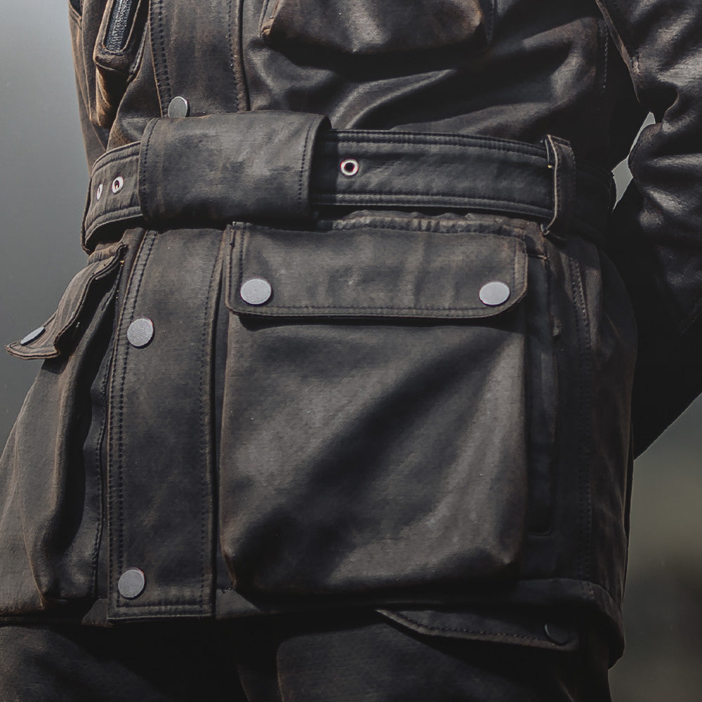 Close-up of jacket’s bottom half on bike, featuring large stow pockets and adjustable waist belt for secure fit