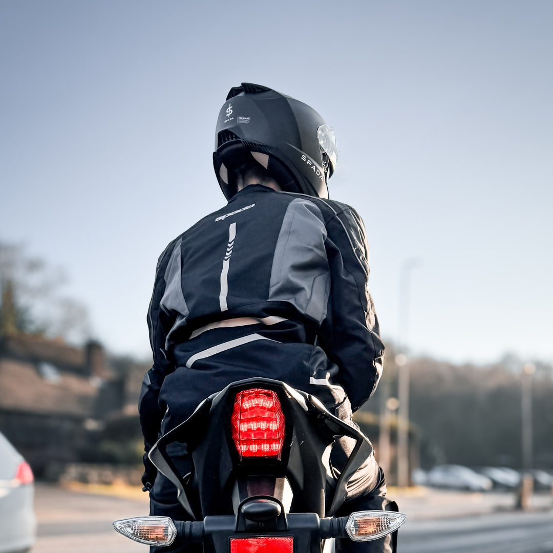back of biker on motorbike wearing black and grey motorcycle jacket for men with matching helmet