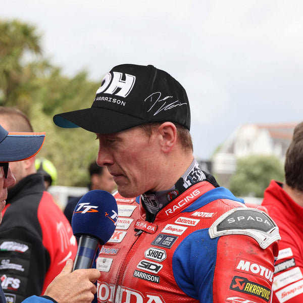 Dean Harrison after a race wearing a black and white cap with the DH logo and his signature on it
