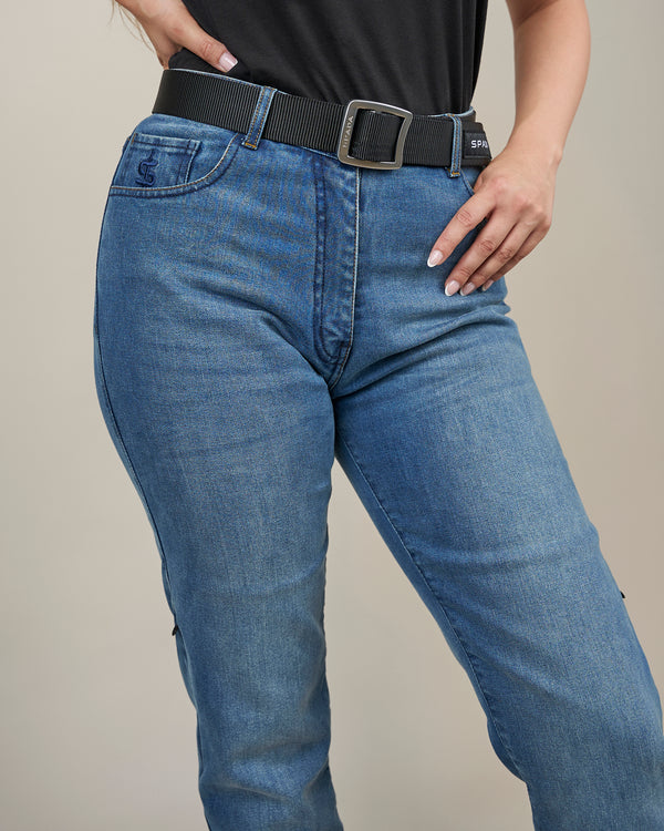Person wearing blue jeans with a black belt on a neutral background