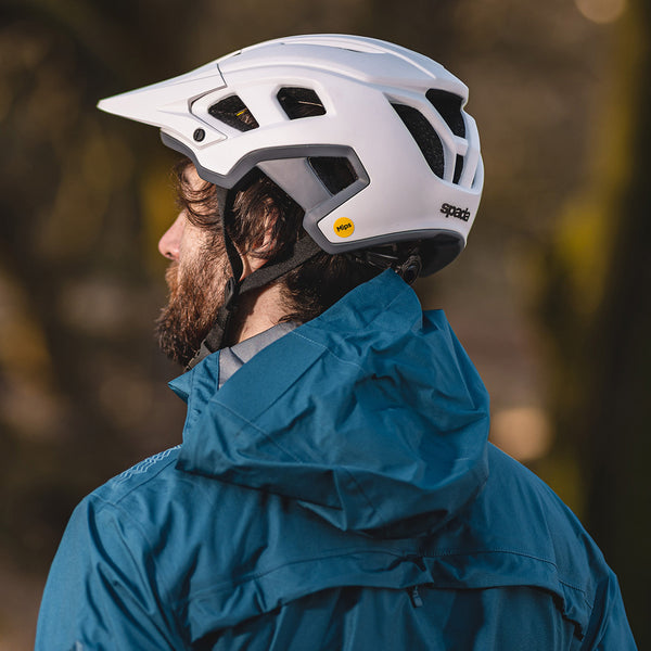 mountain biker wearing blue waterproof jacket with white mountain bike helmet outdoors