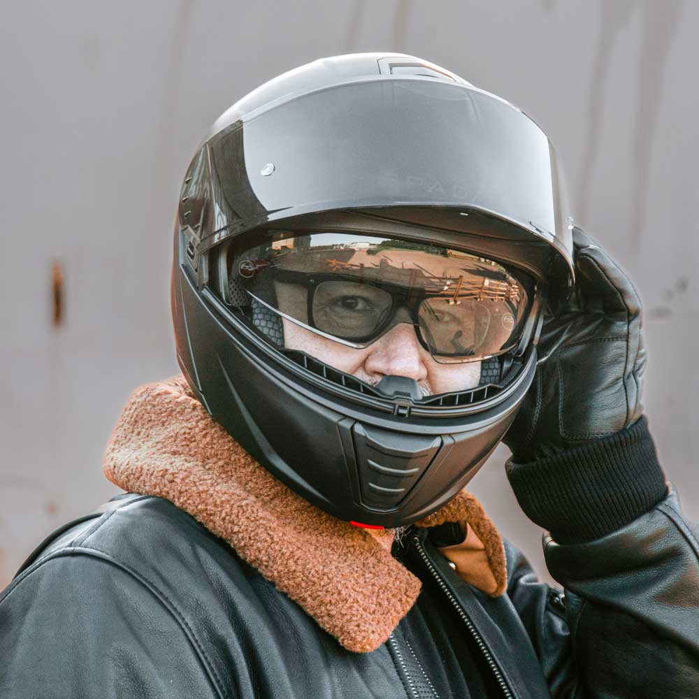 biker wearing black motorbike helmet for men with glasses with visor flipped up