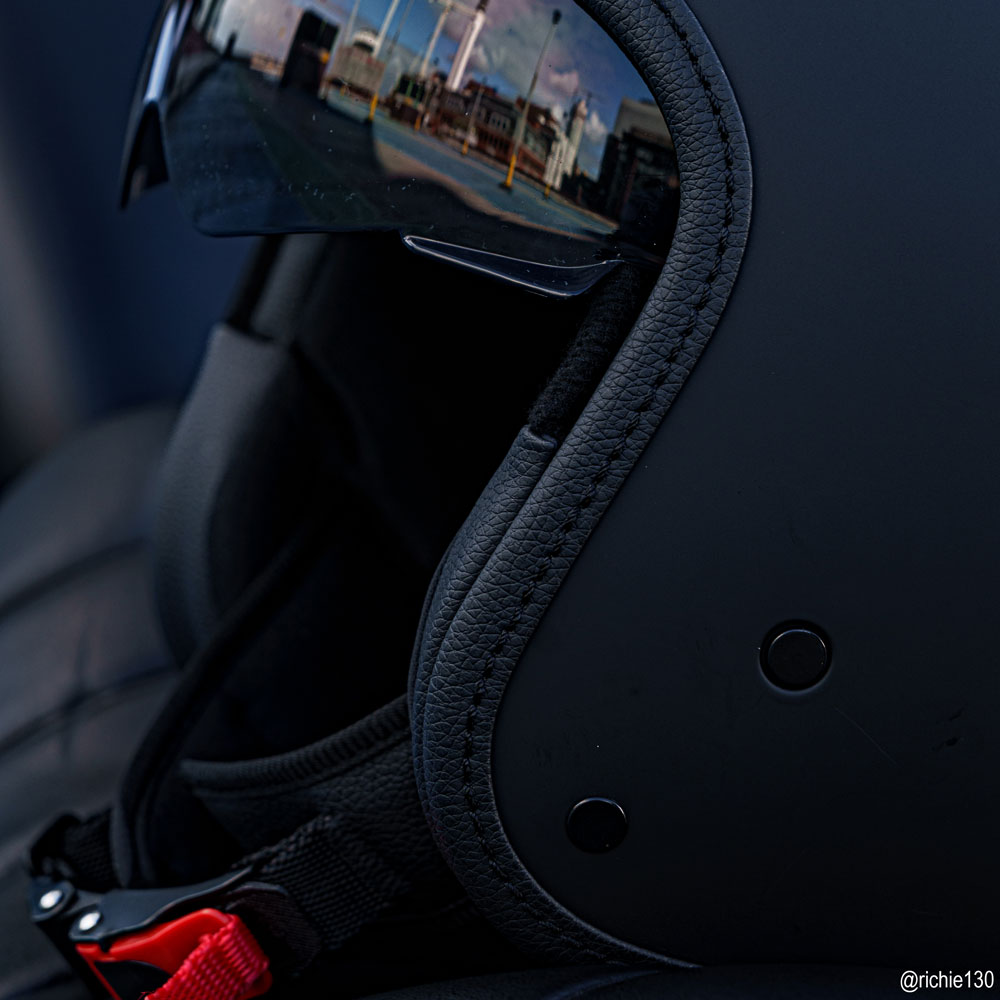 close up of buckle and visor of matte black open face motorbike helmet