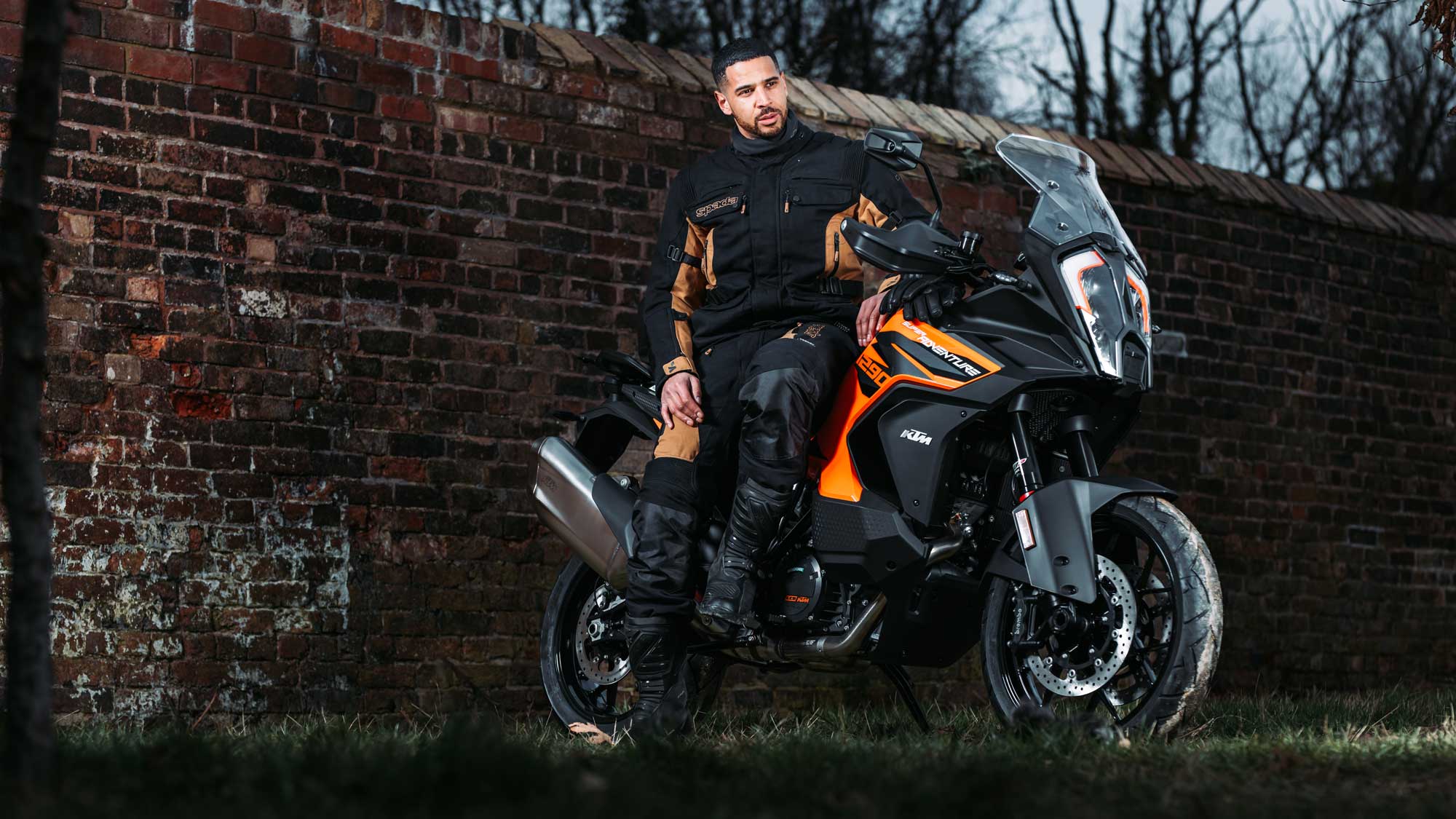 biker on orange motorbike wearing black and brown full motorbike gear
