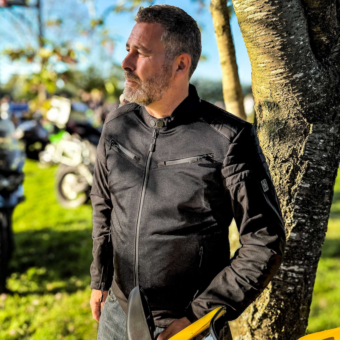 Male rider wearing Cafe Air black motorbike jacket zipped up at bike event, highlighting snug fit and rider-ready style