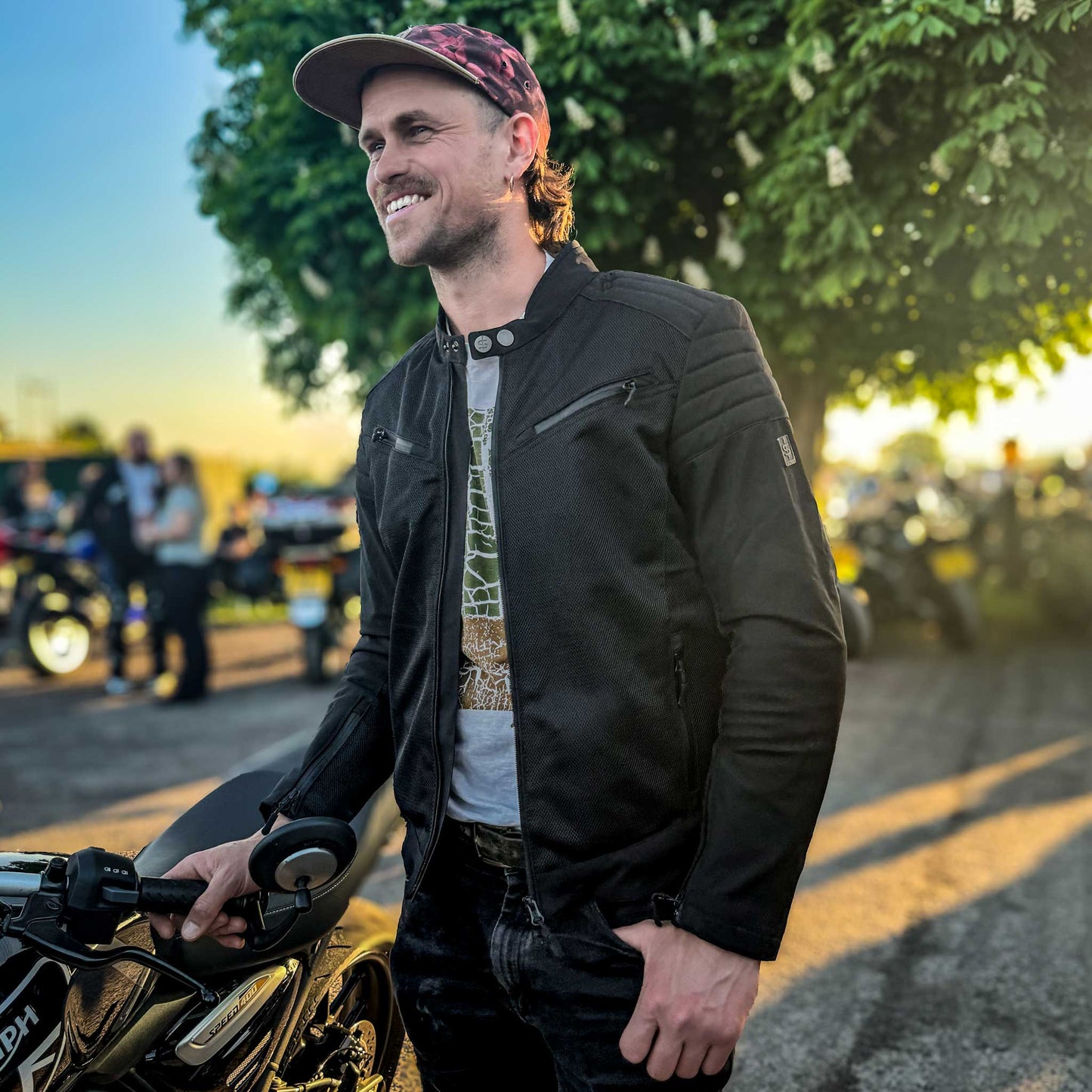 Side angle of biker at meet-up in Cafe Air lightweight jacket worn open, blending style and ventilation