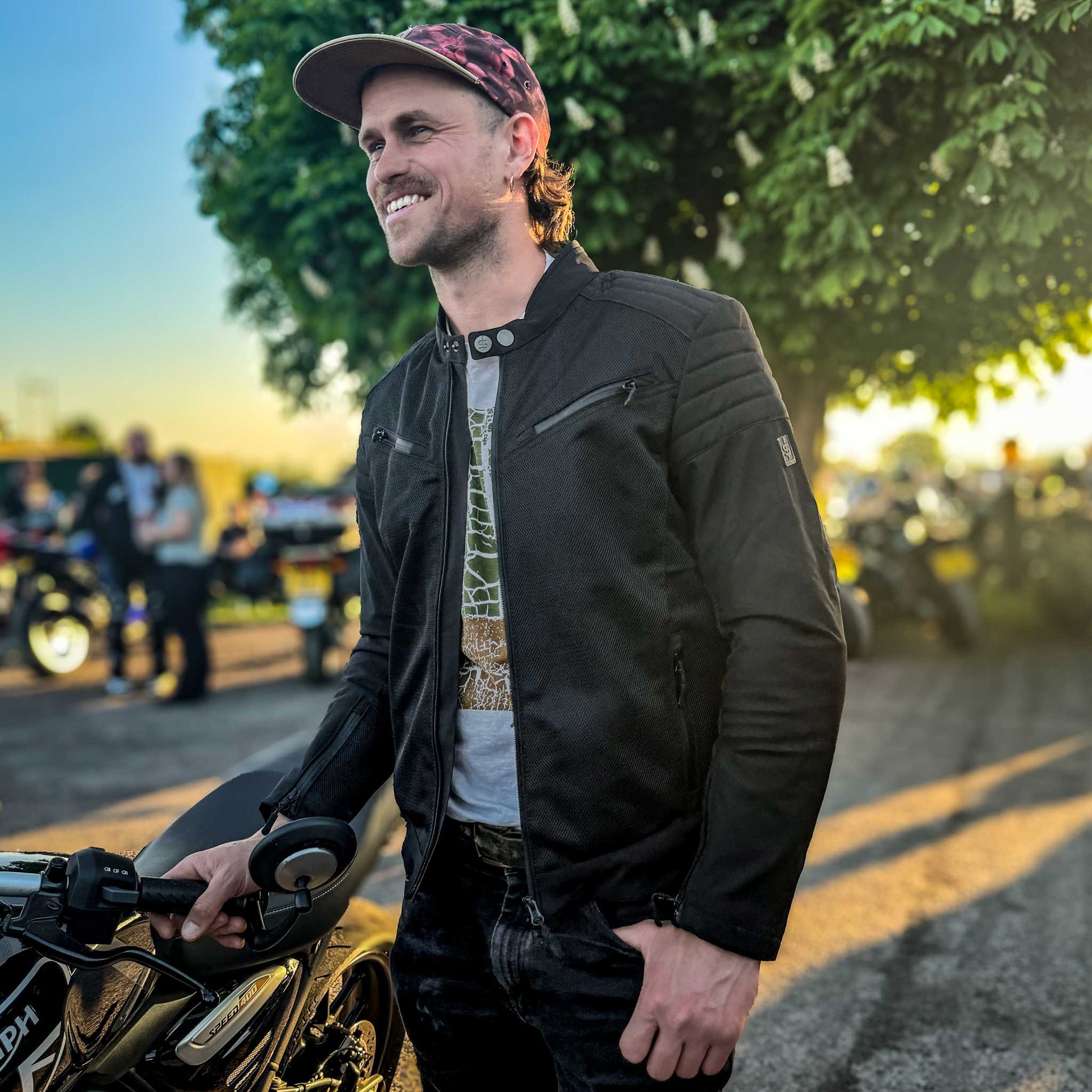 Side angle of biker at meet-up in Cafe Air lightweight jacket worn open, blending style and ventilation