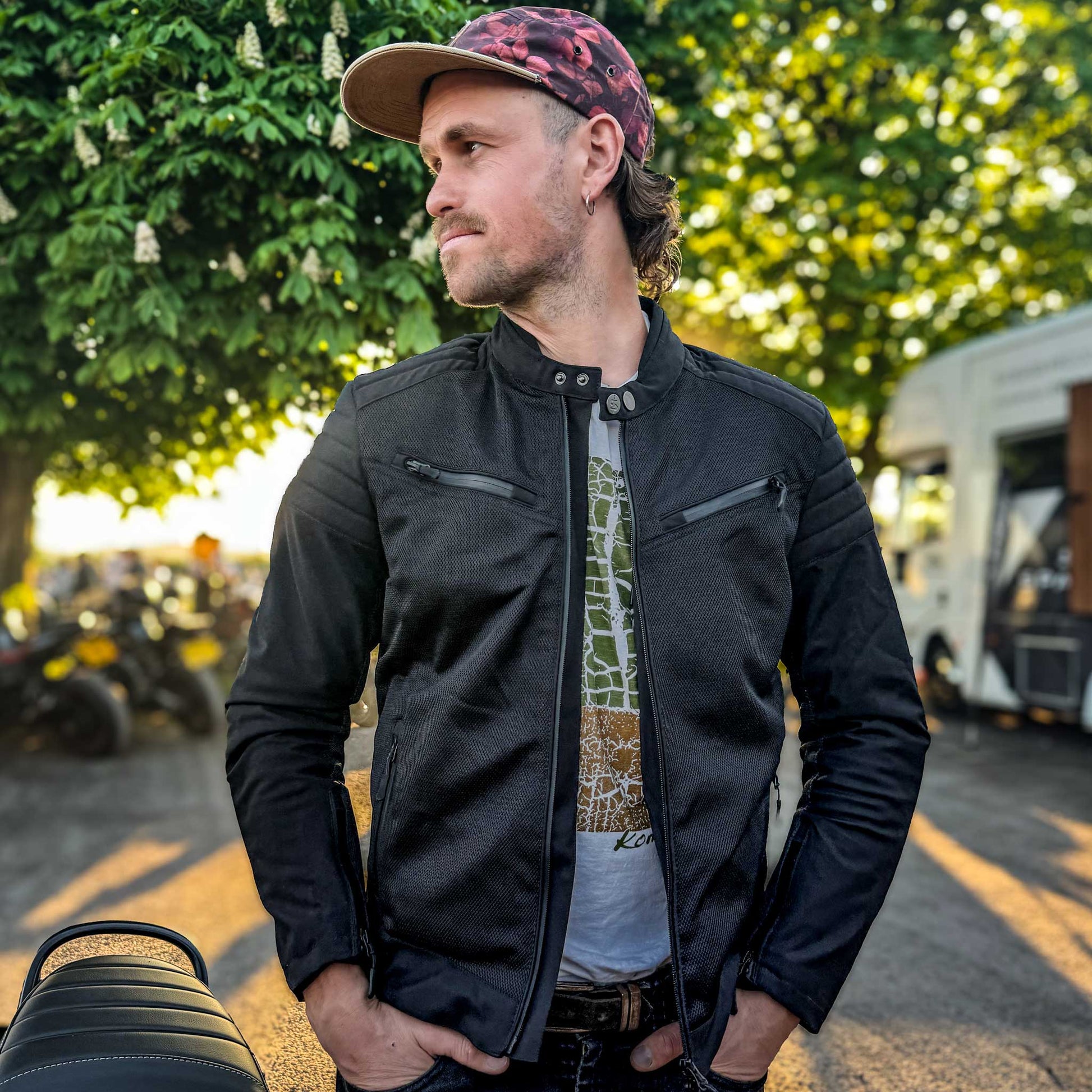 Biker wearing Cafe Air black mesh motorcycle jacket unzipped at bike meet-up, showcasing casual off-bike look