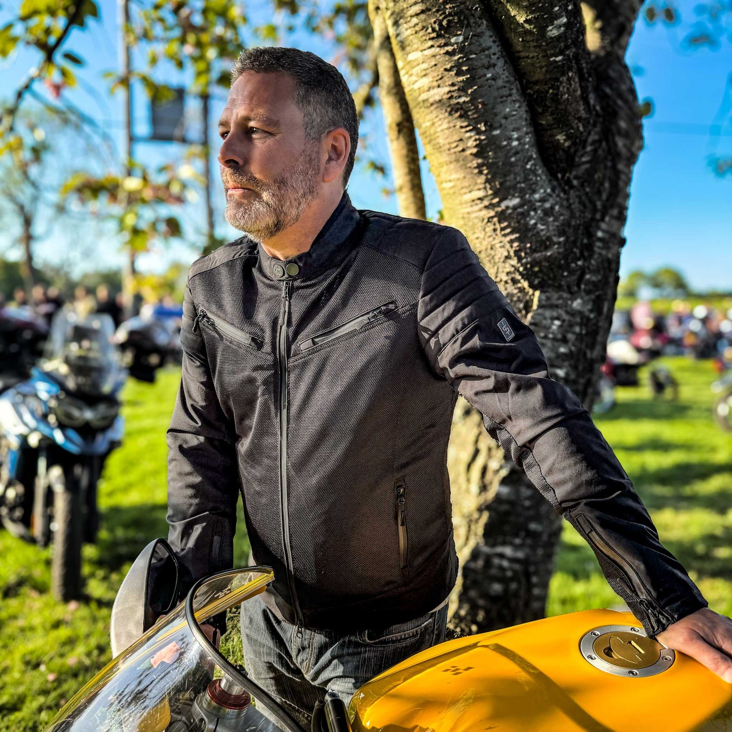 rider wearing zipped up Cafe Air motorcycle jacket for men at biker meet-up, showing clean lines and comfort fit