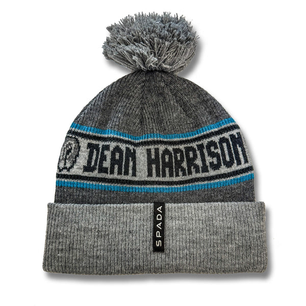 Grey beanie with pom-pom and 'Dean Harrison' branding on a white background