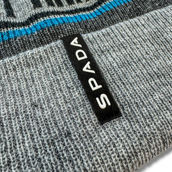 Close-up of a grey bobble hat product with a 'Spada' label.