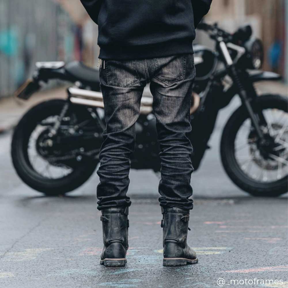 back of biker walking to motorbike wearing black boots and protective jeans for motorbike riding