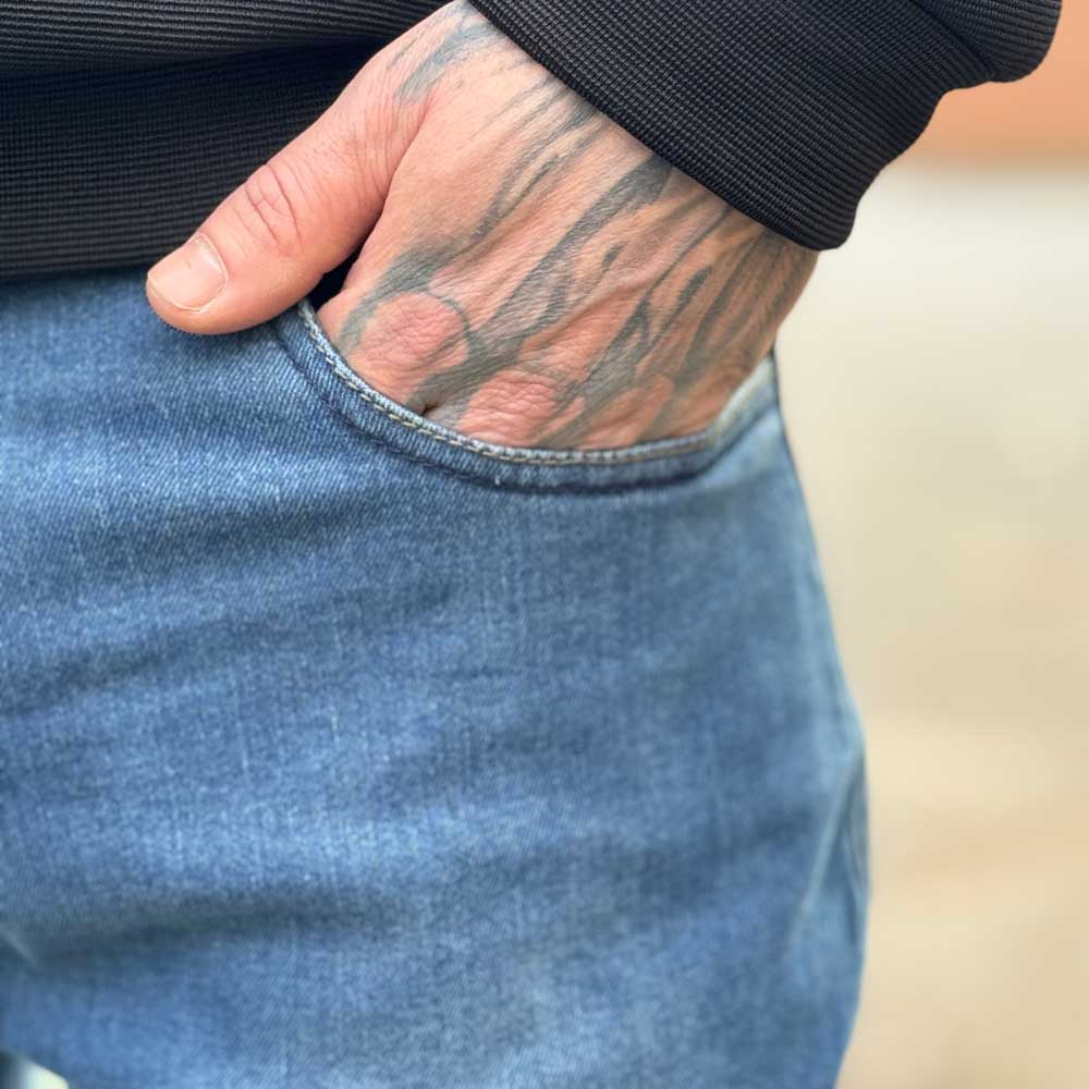 closeup of biker wearing blue aged denim jeans with front pockets
