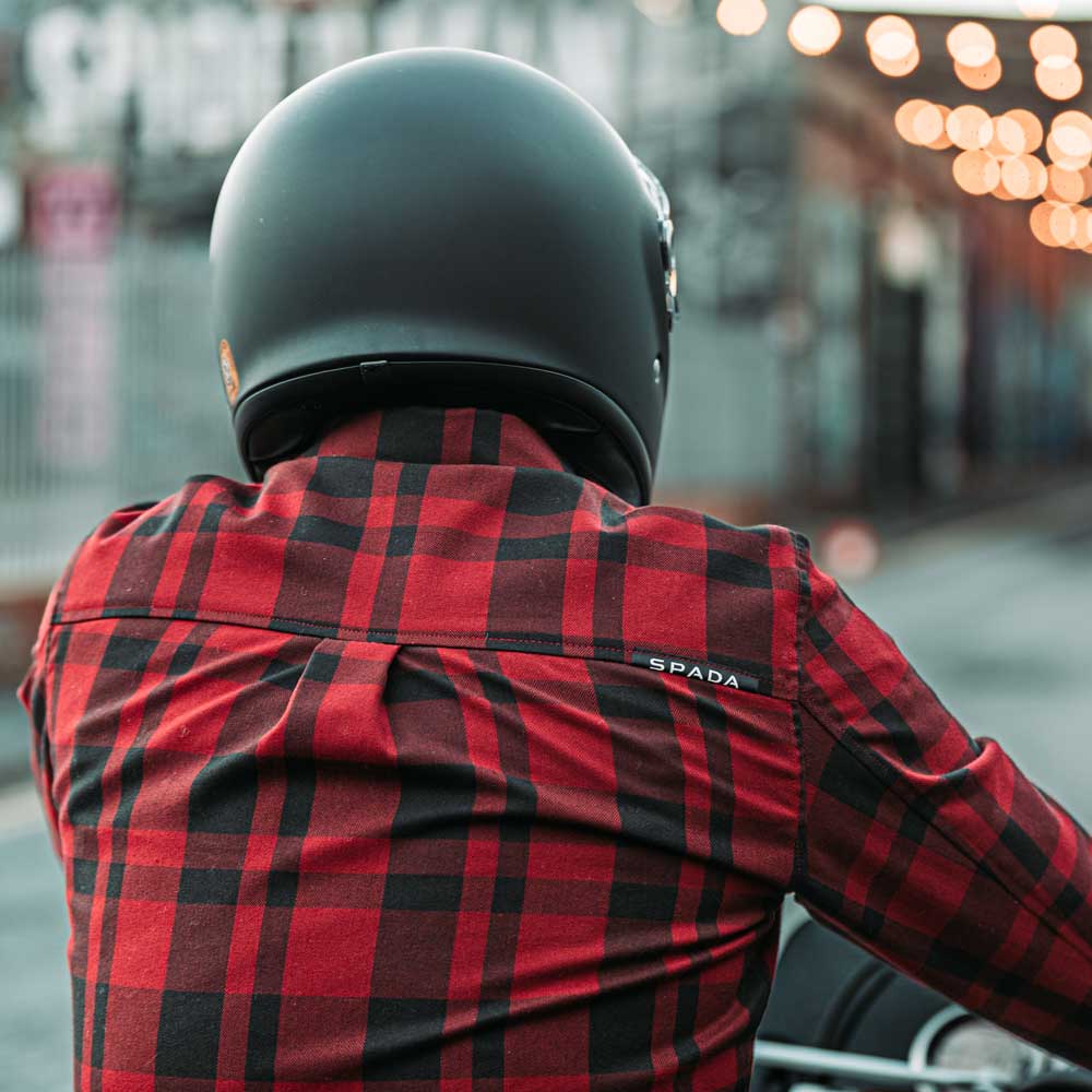 back of motorbike rider wearing black motorbike helmet and black and red motorcycle shirt
