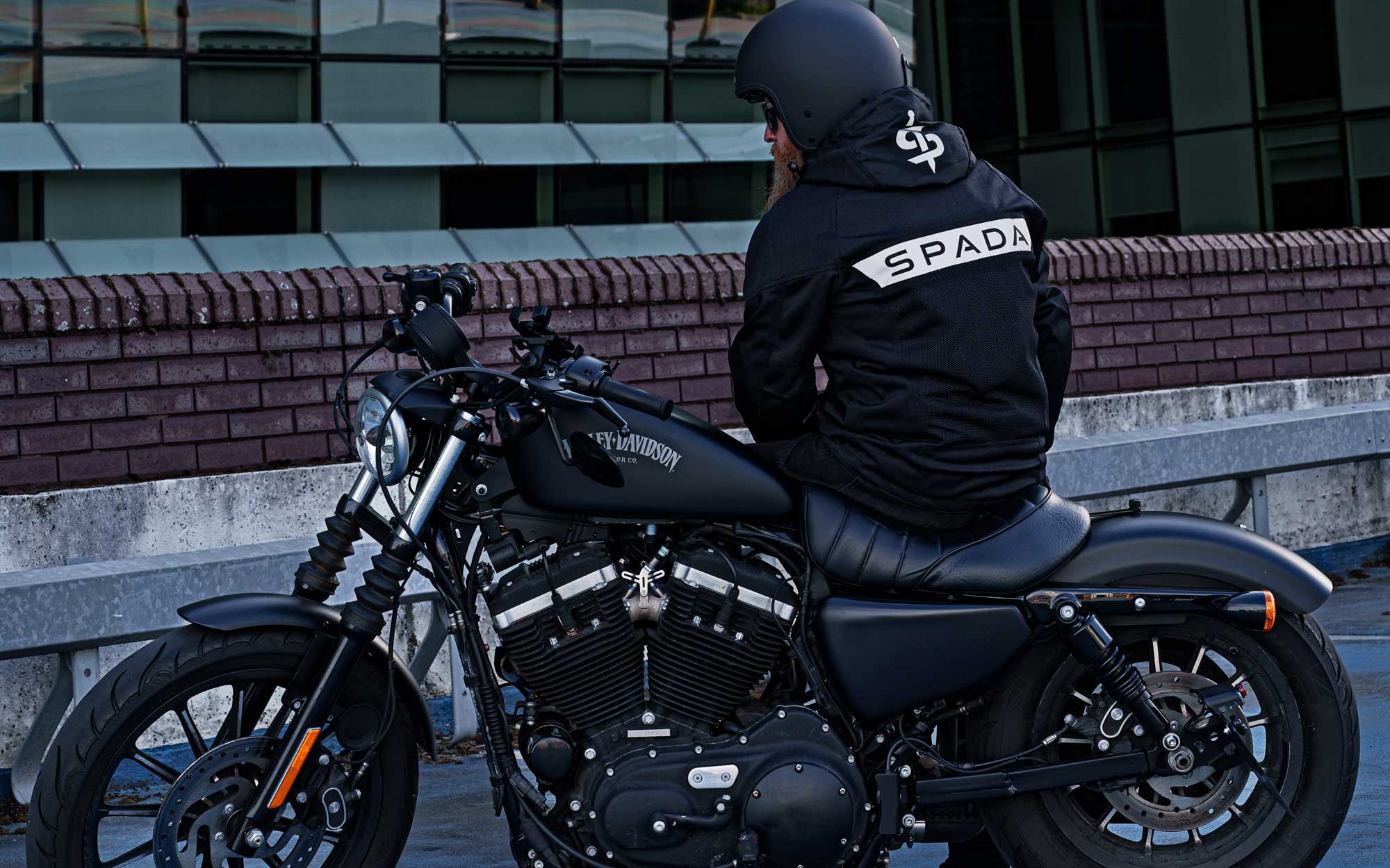 biker sat on harley davidson motorbike wearing black motorcycle jacket for men with reflective on back