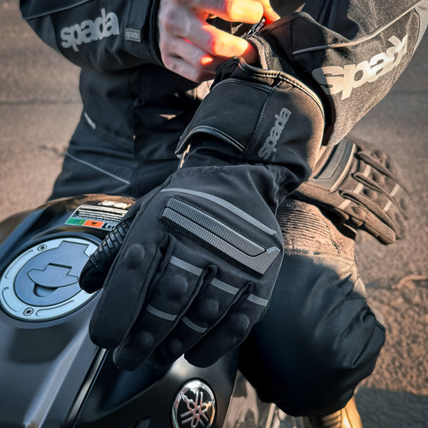 closeup of biker on motorbike putting on black waterproof motorcycle gloves