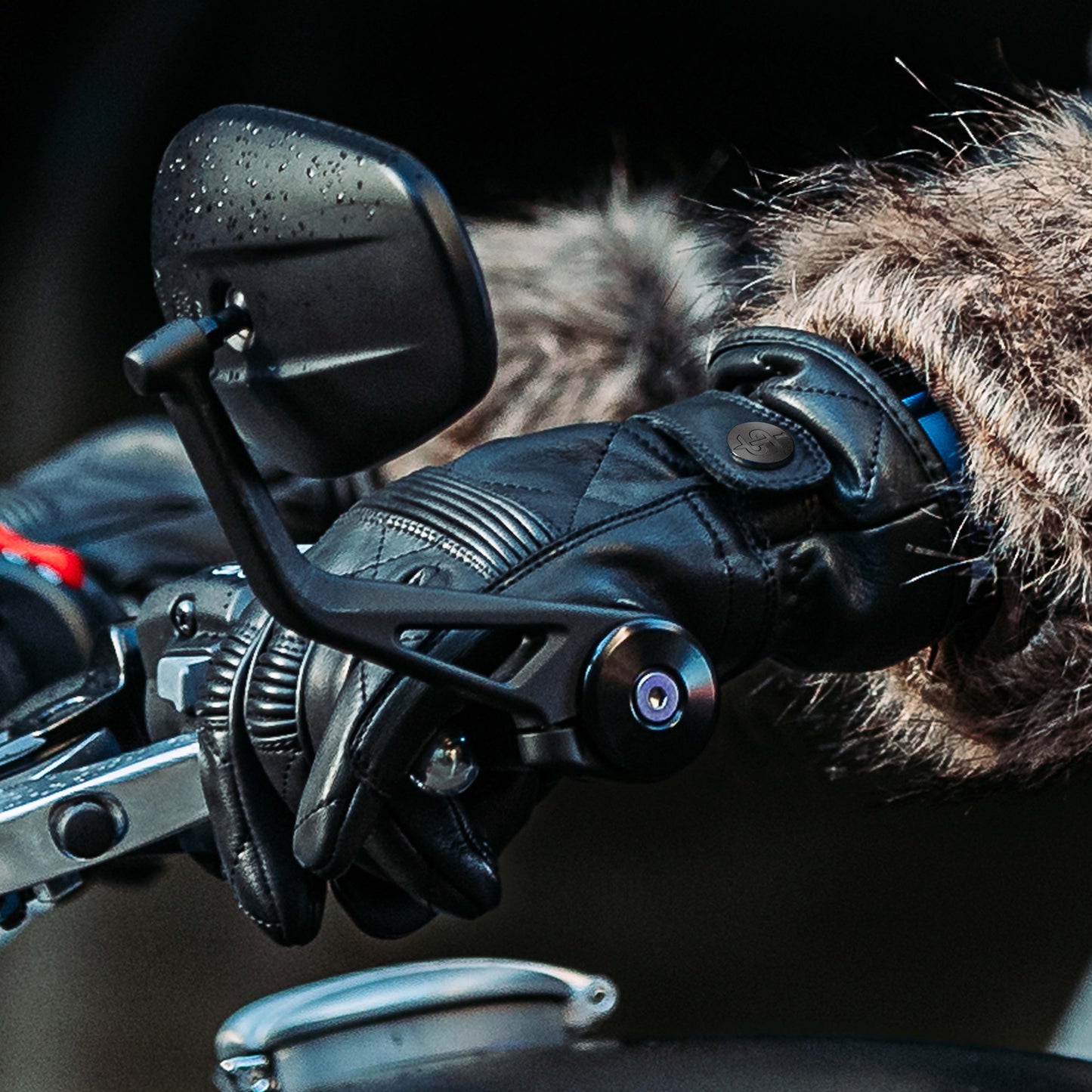 closeup of female biker wearing black leather gloves holding handle bar on motorbike