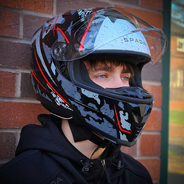 biker wearing black grey and red motorbike helmet with clear visor