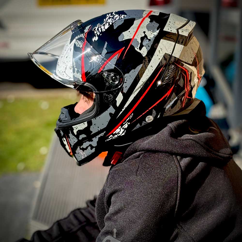 side profile of biker wearing black motorbike hoodie with black and grey motorbike helmet