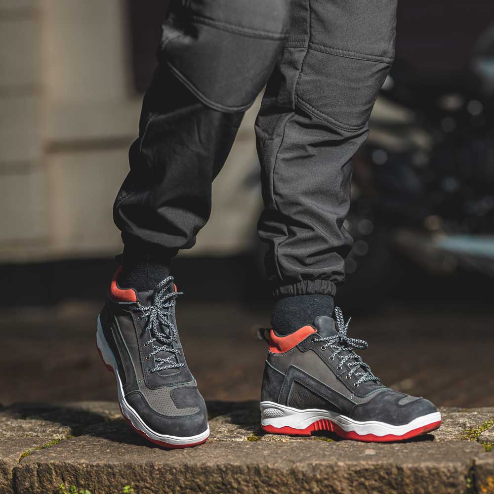 biker wearing black white and red motorcycle trainers after motorbike ride