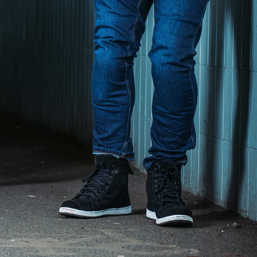 biker wearing black high top lace up motorbike trainers with blue biker jeans