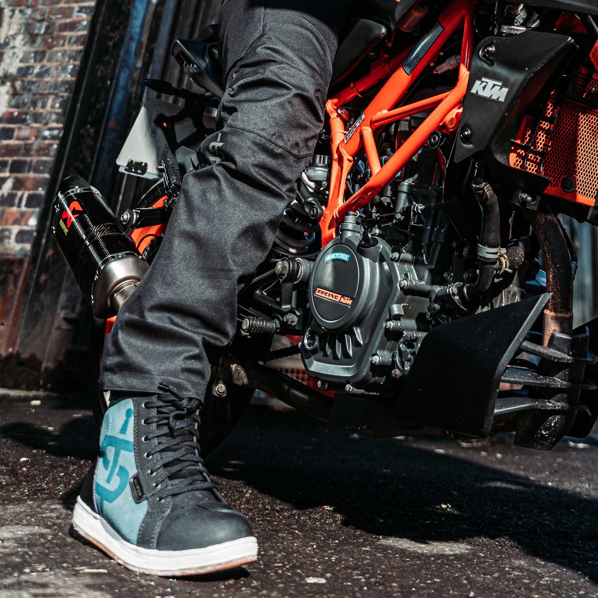 biker wearing black motorcycle trousers for men with black and blue motorcycle trainers