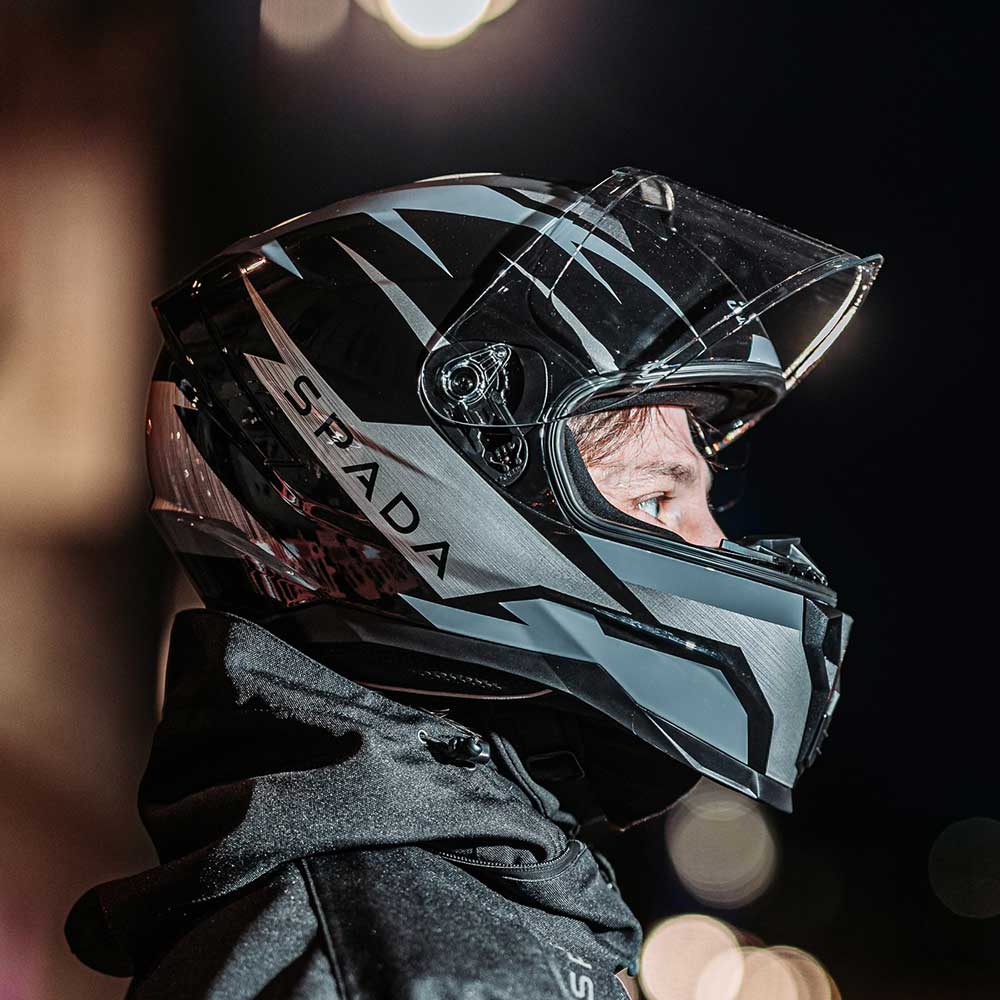 biker wearing black and grey motorbike helmet at night