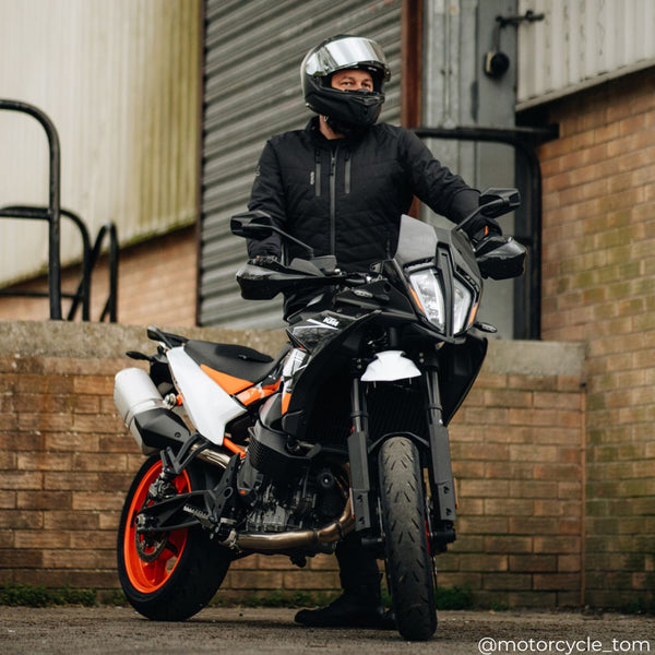 biker wearing black quilted waterproof motorcycle jacket for men on motorcycle with helmet