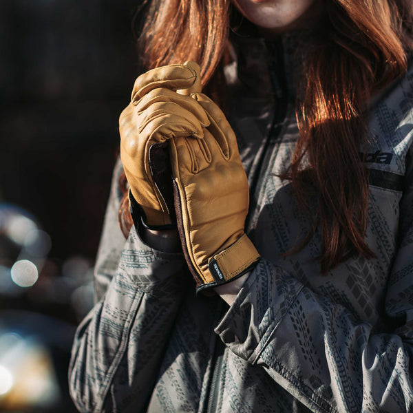 woman biker wearing a pair of tan yellow motorcycle gloves