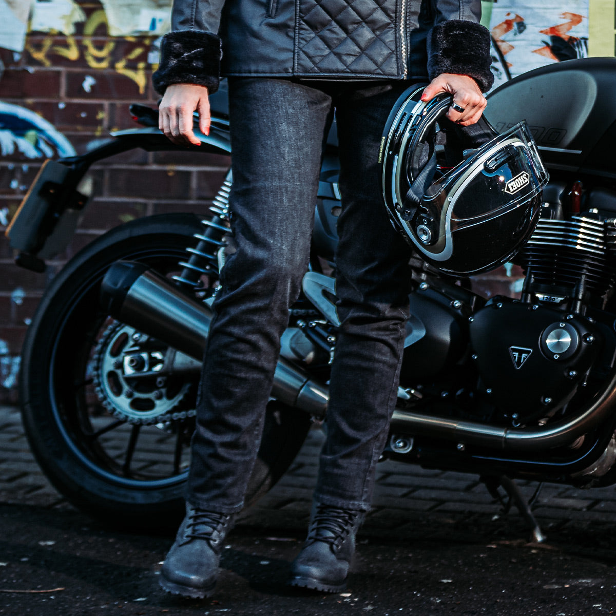 Woman wearing black washed motorcycle jeans, standing confidently to show the slim fit and stylish design for women riders.