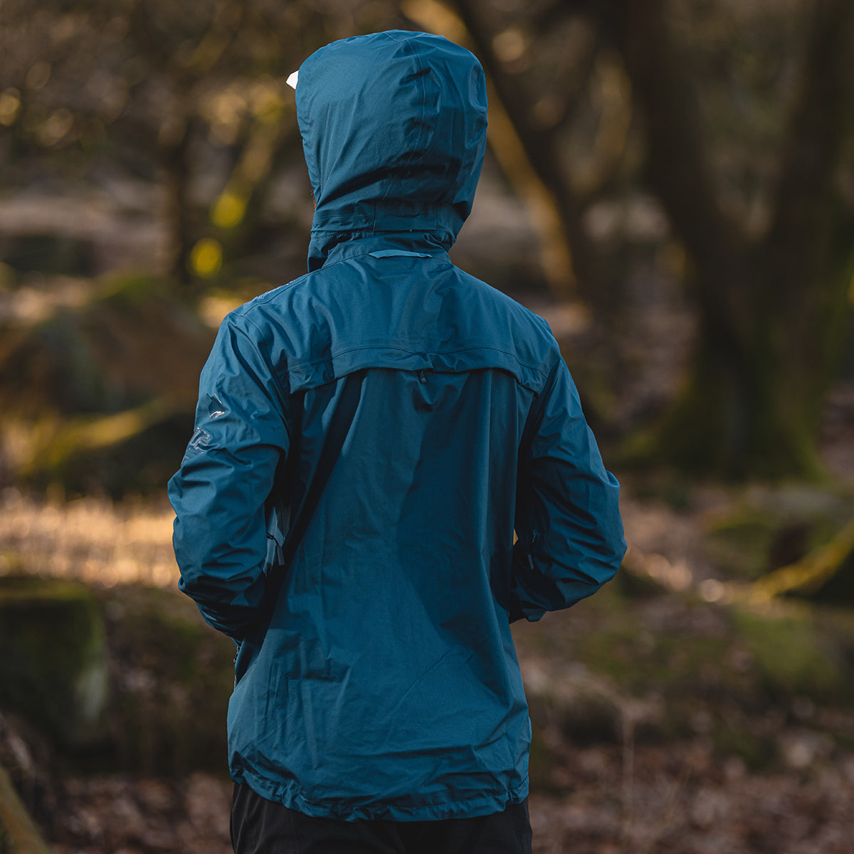 back of biker wearing blue waterproof jacket with hood