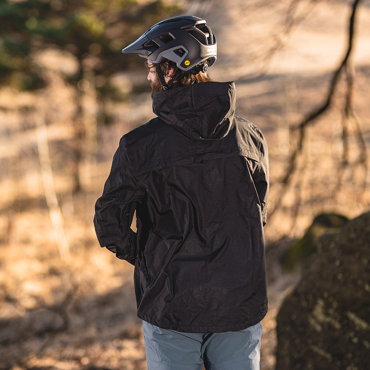 back of biker wearing black helmet and black waterproof jacket