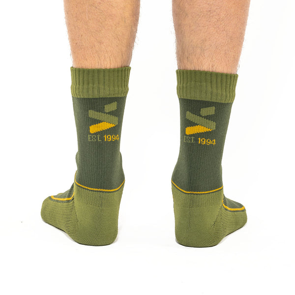 A pair of olive green MTB socks with yellow and black branding around the ankle area.