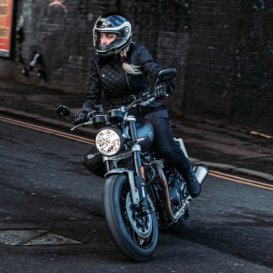 lady biker wearing black leather motorcycle jacket with shoei helmet riding in street