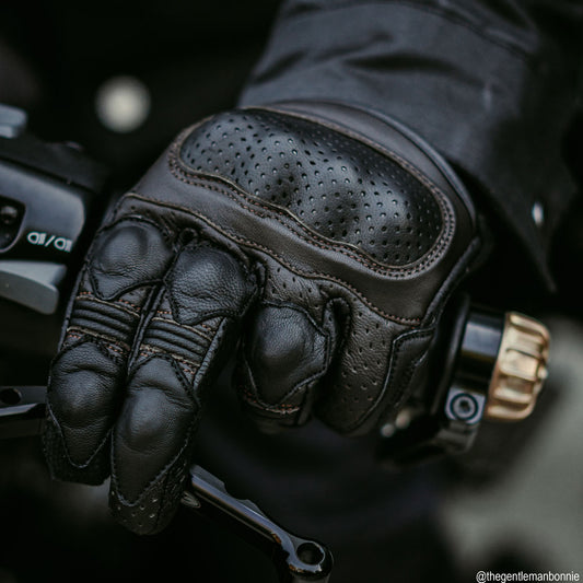 black leather motorcycle gloves with brown stitching worn by biker on a ride