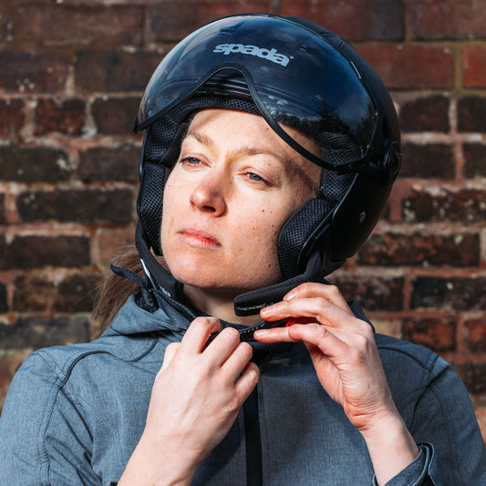 woman strapping on a black spada motorcycle helmet