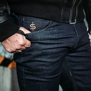 biker wearing raw denim jeans for men with closeup of spada embroidered pocket