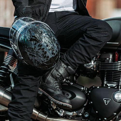 biker wearing black motorcycle trousers paired with matching black boots and motorbike helmet
