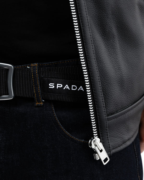 Close-up of a black jacket with a Spada logo on a dark background