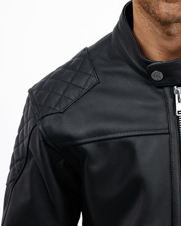 Close-up of a black leather jacket with quilted shoulder design on a white background