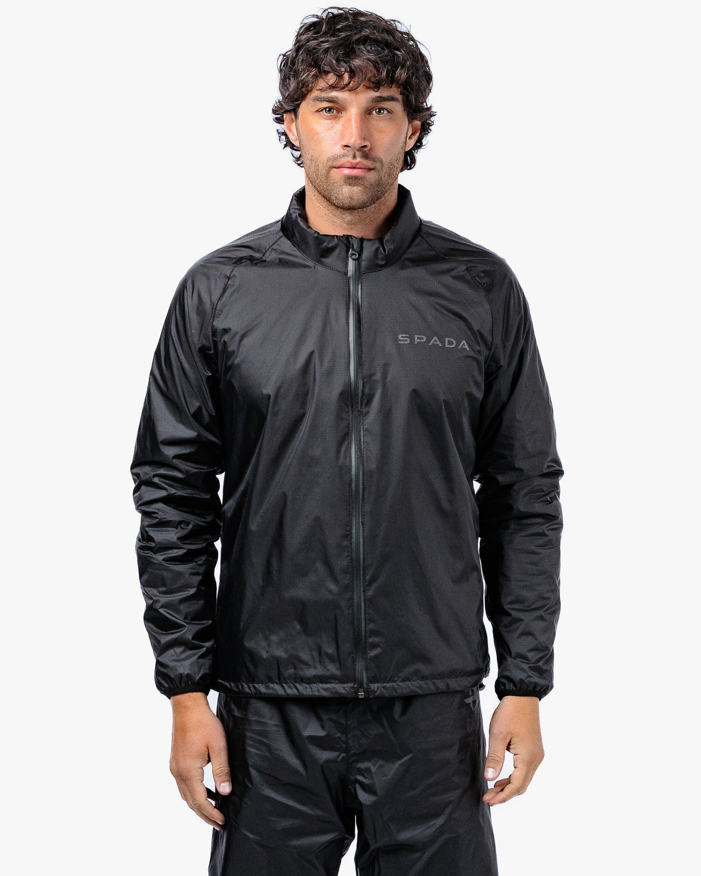 Man wearing a black Spada rain suit on a white background