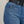Close-up of blue jeans with a brand logo on the pocket against a neutral background