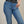 Person wearing blue jeans with a black belt on a neutral background