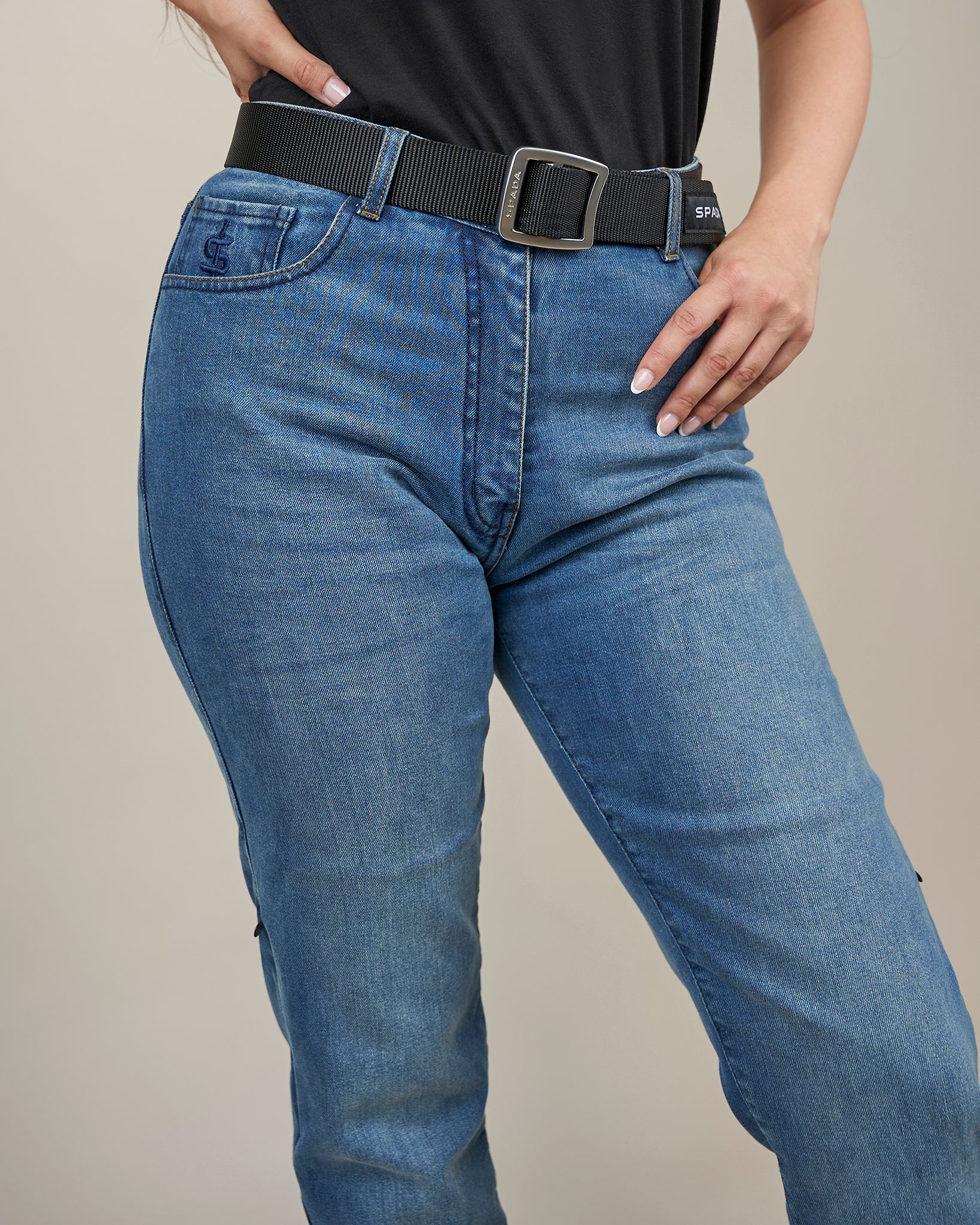 Person wearing blue jeans with a black belt on a neutral background