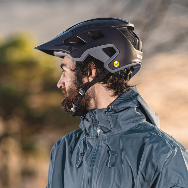 side profile of mountain biker wearing waterproof jacket and black mtb helmet outdoors